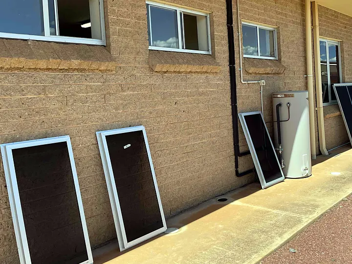 Framed window screens leaning against a brick wall beside windows